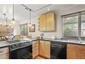 Well-lit kitchen featuring wood cabinets, black countertops, and a stainless-steel dishwasher at 6235 E 6Th Avenue Pkwy, Denver, CO 80220