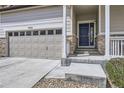 Close up view of a home's entrance featuring a two car garage and covered porch at 9751 Mobile St, Commerce City, CO 80022