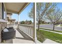 Relaxing covered porch with seating overlooking a serene street and a lush green lawn at 9751 Mobile St, Commerce City, CO 80022
