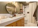 Stylish bathroom featuring a round mirror, modern vanity, and a shower with white tile surround at 12920 W 24Th Pl, Golden, CO 80401
