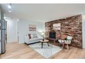 Bright living room featuring a brick fireplace, modern decor, and wood-look floors at 155 S Pennsylvania St # 101, Denver, CO 80209