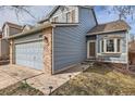 Close-up of a two-story home featuring light blue siding with brick accents, a two-car garage, and a walkway at 3532 Morning Glory Dr, Castle Rock, CO 80109
