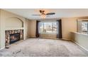 Spacious living room with a stone fireplace, ceiling fan, large window, and neutral colored walls at 3532 Morning Glory Dr, Castle Rock, CO 80109