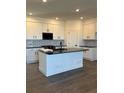 Modern kitchen features white cabinets, black hardware, black countertops and backsplash with center island at 14295 Currant St, Broomfield, CO 80020