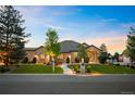 Inviting brick home featuring a lush green lawn, mature trees, and tasteful landscaping at 13087 W 27Th Ln, Golden, CO 80401