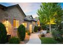 Attractive brick home with lush landscaping, a curved walkway, and tasteful outdoor lighting at 13087 W 27Th Ln, Golden, CO 80401