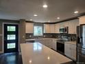 Modern kitchen featuring white cabinetry, stainless steel appliances, a stylish backsplash, and a large island with countertop seating at 795 Vivian Ct, Lakewood, CO 80401