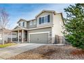 Two-story home featuring a covered front porch, and a two-car garage with stone accents at 574 Solano Dr, Brighton, CO 80603