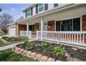 Charming home with brick accents, white porch railing, and beautiful landscaping and flowers at 7343 S Ivy Way, Centennial, CO 80112