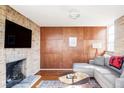 Cozy living room with a brick fireplace, wood paneled accent wall and comfortable seating at 3050 S Marion St, Englewood, CO 80113