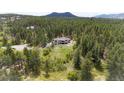 Breathtaking aerial view of a secluded home surrounded by lush forest, offering privacy and scenic mountain views at 1988 Lake Dr, Larkspur, CO 80118