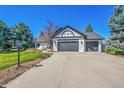 Charming exterior features a three-car garage, lush lawn, and mature trees at 44 Spyglass Dr, Littleton, CO 80123