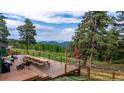 Expansive wooden deck with outdoor seating and stunning views of rolling hills and lush greenery at 8537 S Doubleheader Hwy, Morrison, CO 80465