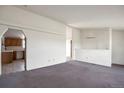 Open living area with carpet flooring, neutral walls, and kitchen access at 554 E Pleasant Ave, Byers, CO 80103
