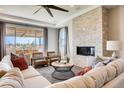 Cozy living room featuring a stone fireplace, plush seating, large windows, and stylish modern décor at 13806 Honey Hush Trl, Parker, CO 80134
