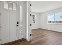 Inviting entryway featuring a modern white door, light-filled room, and elegant hard wood flooring at 8644 Pennycress Dr, Littleton, CO 80125
