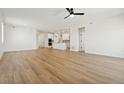 Open-concept living room with hardwood floors, white walls, ceiling fan, and kitchen view at 42998 Colonial Trl, Elizabeth, CO 80107