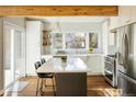 Sun-drenched kitchen with a center island, pendant lights, wood beams, and an open view to the backyard at 780 Utica Ave, Boulder, CO 80304