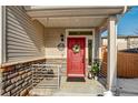 Charming front porch with a bright red door, stone accents, and seasonal decorations at 10232 Yampa Ct, Commerce City, CO 80022