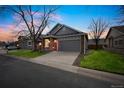 Charming home at dusk featuring a well-manicured lawn, mature trees, and a two-car garage at 9630 W La Salle Ave, Lakewood, CO 80227