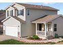 Charming two-story home featuring a covered porch, attached garage, and well-manicured landscaping at 7720 Brown Bear Way, Littleton, CO 80125