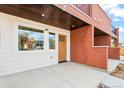Close up of a modern townhome featuring brick facade, wood door, and covered entry for added curb appeal at 1052 N Knox Ct, Denver, CO 80204