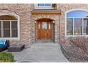 Inviting front entrance showcasing a stylish wooden door with stone surround and well-lit entryway at 1313 Jade Ln, Longmont, CO 80504