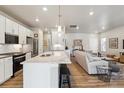 Open concept kitchen with a marble island, white cabinets, stainless appliances, and a seamless view into the living area at 12820 Inca St, Westminster, CO 80234