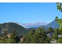 Scenic view of the mountains and neighborhood homes nestled among lush green trees at 26176 Sweetbriar Trl, Evergreen, CO 80439