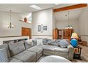 Bright, open concept living room features vaulted ceiling with exposed wood beam, skylights and gray sectional sofa at 4231 S Fairplay Cir # A, Aurora, CO 80014