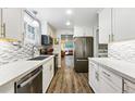 Modern kitchen featuring white cabinets, stainless steel appliances, and sleek countertops with view to the living room at 8736 W 46Th Ave, Wheat Ridge, CO 80033