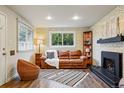 Inviting living room features a brick accent wall, a cozy fireplace, and ample natural light from the large window at 8736 W 46Th Ave, Wheat Ridge, CO 80033
