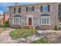 Charming brick home with red door, bay windows, landscaped yard, and a stone walkway leading to the front entrance at 1000 N Monaco Pkwy, Denver, CO 80220