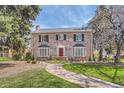 Charming brick home with red door, bay windows, landscaped yard, and a stone walkway leading to the front entrance at 1000 N Monaco Pkwy, Denver, CO 80220