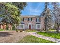 Charming brick home with red door, bay windows, landscaped yard, and a stone walkway leading to the front entrance at 1000 N Monaco Pkwy, Denver, CO 80220