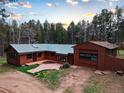 Aerial view of home featuring wood siding, a green metal roof, and an oversized garage at 9123 Booker Ln, Conifer, CO 80433