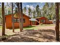 Exterior view of home featuring wood siding and a green metal roof amongst the trees at 9123 Booker Ln, Conifer, CO 80433