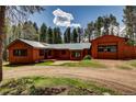 Exterior view of home featuring wood siding, a green metal roof and an oversized garage at 9123 Booker Ln, Conifer, CO 80433