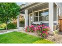Close-up of a charming front porch with a swing and vibrant flower bushes in a beautifully landscaped yard at 6940 Clay St, Denver, CO 80221