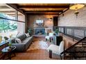 Comfortable living room with brick walls, a cozy fireplace, and large windows offering natural light at 21868 Mountsfield Dr, Golden, CO 80401