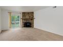 Bright living room with a stone fireplace, sliding glass door, and neutral carpet at 4400 S Quebec St # 105K, Denver, CO 80237