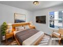 Cozy bedroom featuring a sleek wooden bed frame, plush rug, large TV, and calming natural light at 4940 Akron St, Denver, CO 80238