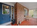 Cozy covered front porch with red wood floors, brick siding, and traditional detailing at 18 Blue Sage, Littleton, CO 80127