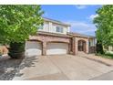 Residential home featuring a red brick facade, arched doorway, two-car garage, and well-maintained landscaping at 10155 Charissglen Ln, Littleton, CO 80126