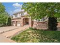 Two-story home with brick facade, arched entryway, two-car garage, and a professionally landscaped front yard at 10155 Charissglen Ln, Littleton, CO 80126