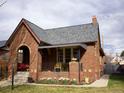 Charming brick home featuring a covered porch, complemented by a well-maintained lawn and blossoming flowers at 1840 S Grant St, Denver, CO 80210