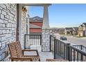 Cozy front porch featuring a sitting area, stone-detailed columns, and a view of the street at 9786 Rosalee Peak St, Littleton, CO 80125