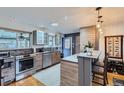 Modern kitchen boasts stainless steel appliances, gray cabinetry, and breakfast bar with pendant lighting at 3020 Niagara St, Denver, CO 80207