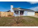 Charming light blue home with a two-car garage and solar panels against a clear blue sky at 1451 S Quitman St, Denver, CO 80219