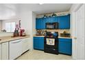 Kitchen boasting blue cabinets with black hardware, white appliances and tile flooring at 10223 Vine Ct, Thornton, CO 80229